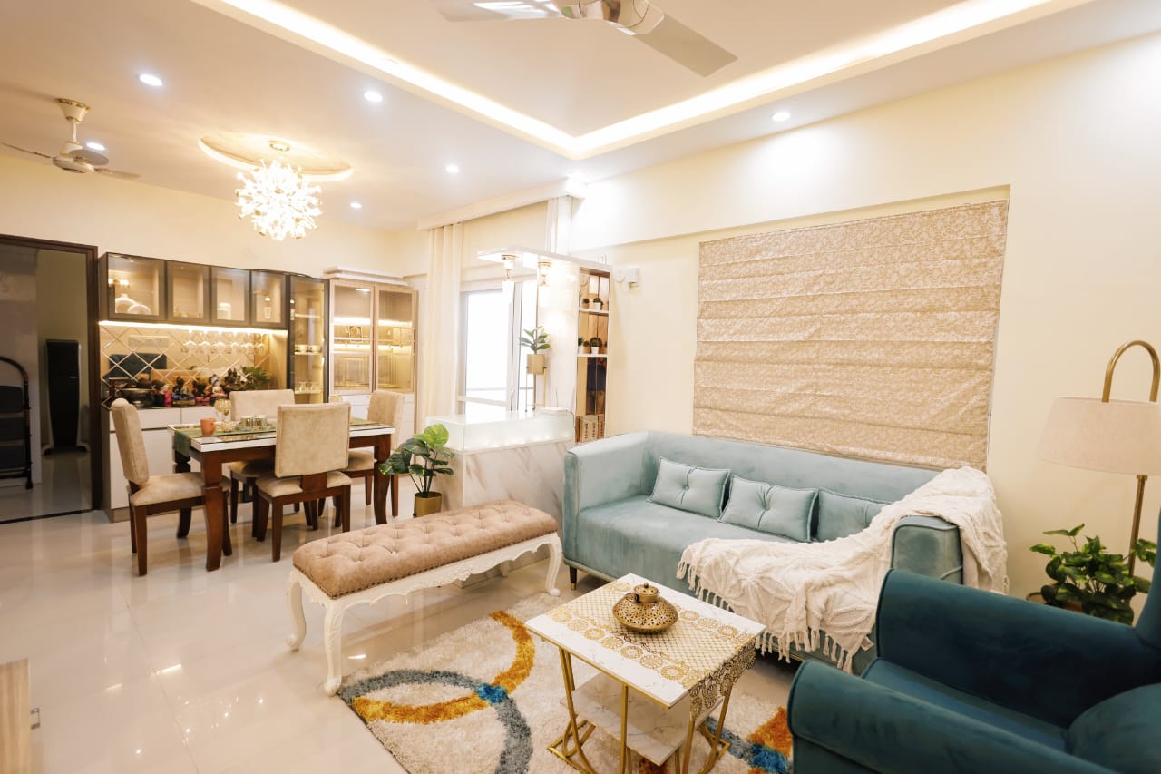 Open living-dining space with a teal velvet tufted sofa and matching tufted bench facing a marble-and-brass coffee table