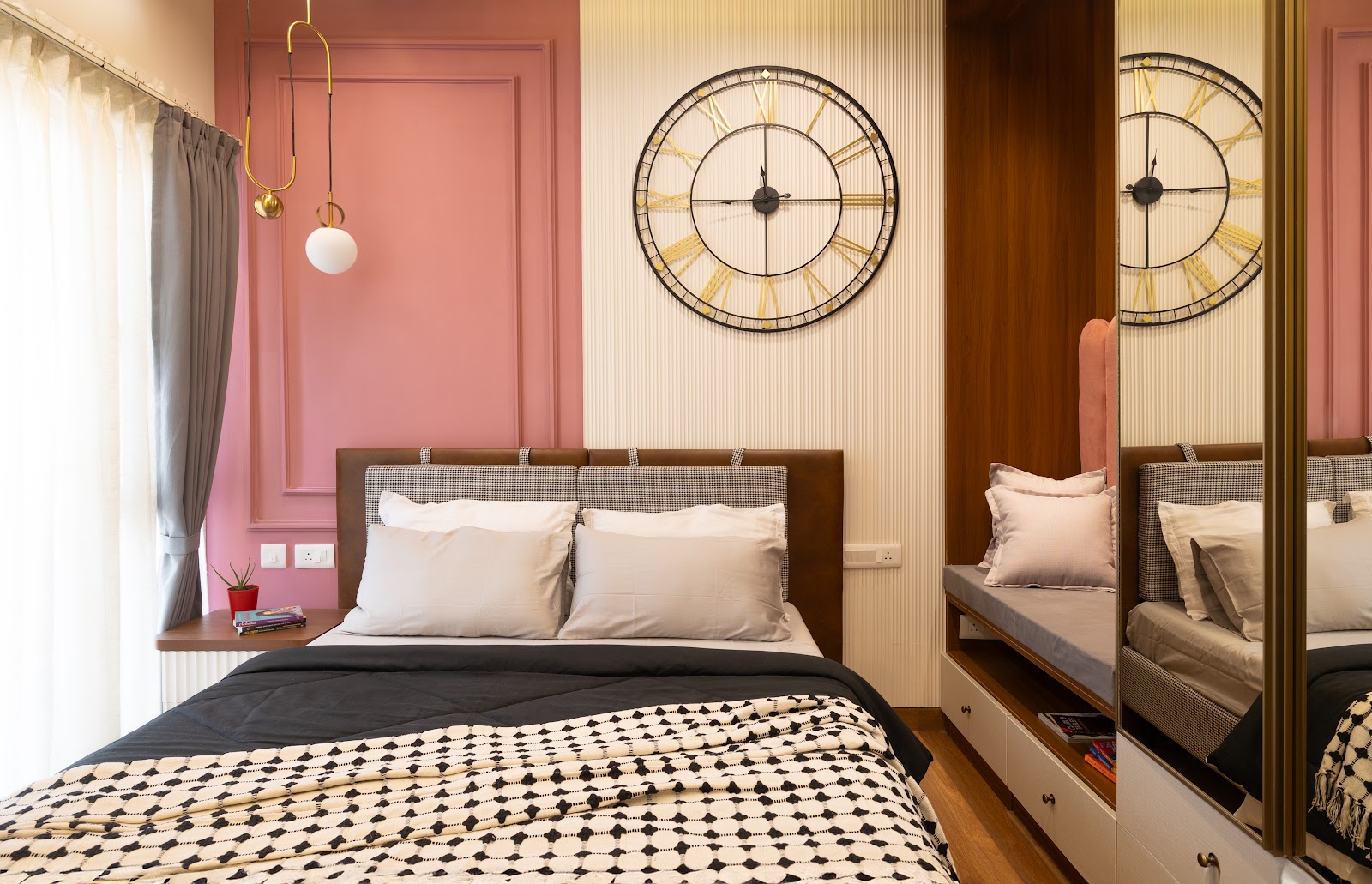 Bedroom with a dusty-pink moulded accent wall, an oversized gold-and-black wall clock, a houndstooth-check upholstered headboard