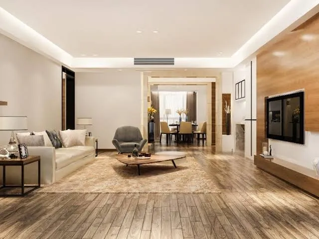 Render of an open living room with a cream sofa and round wooden coffee table on a jute-toned rug, a wood-clad TV wall to the right