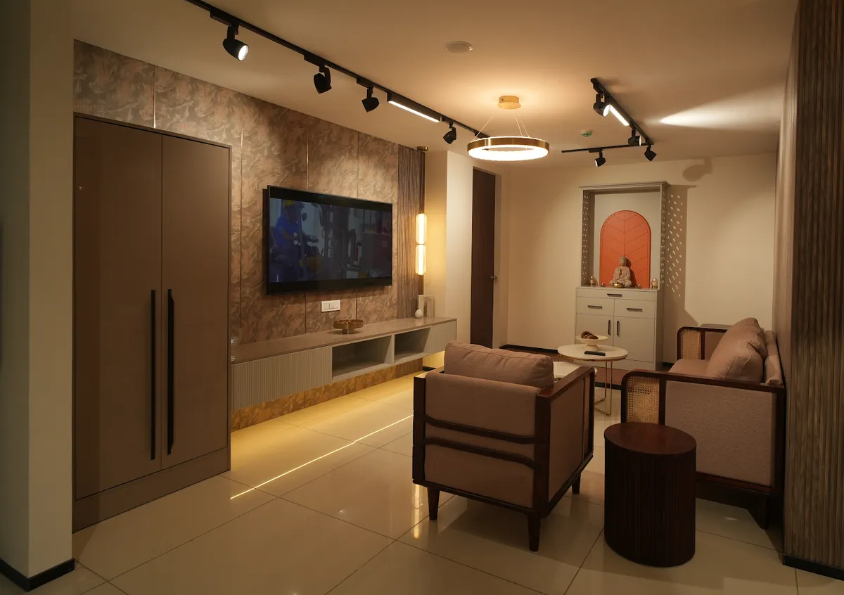 Warmly lit living room with a stone-print TV panel over an under-lit floating console, black track spots on the ceiling