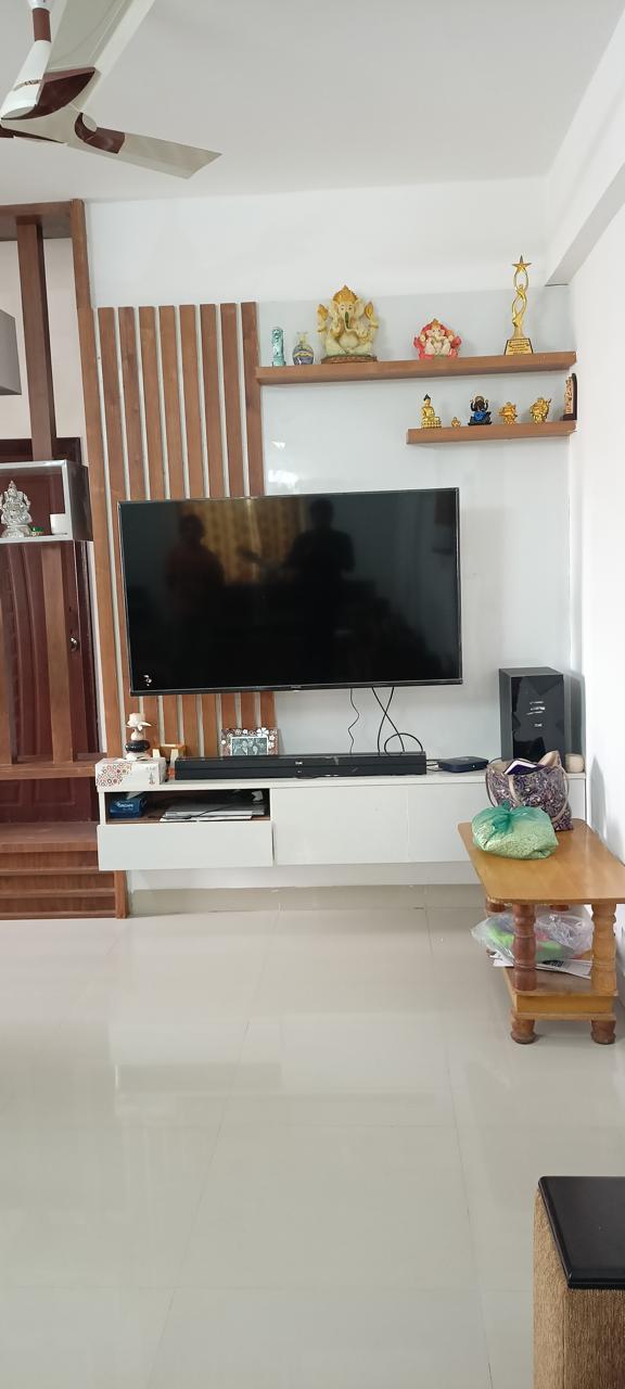 Living room TV wall with fluted wood panelling and a floating console, a wood coffee table with stored items in front, staircase visible alongside.