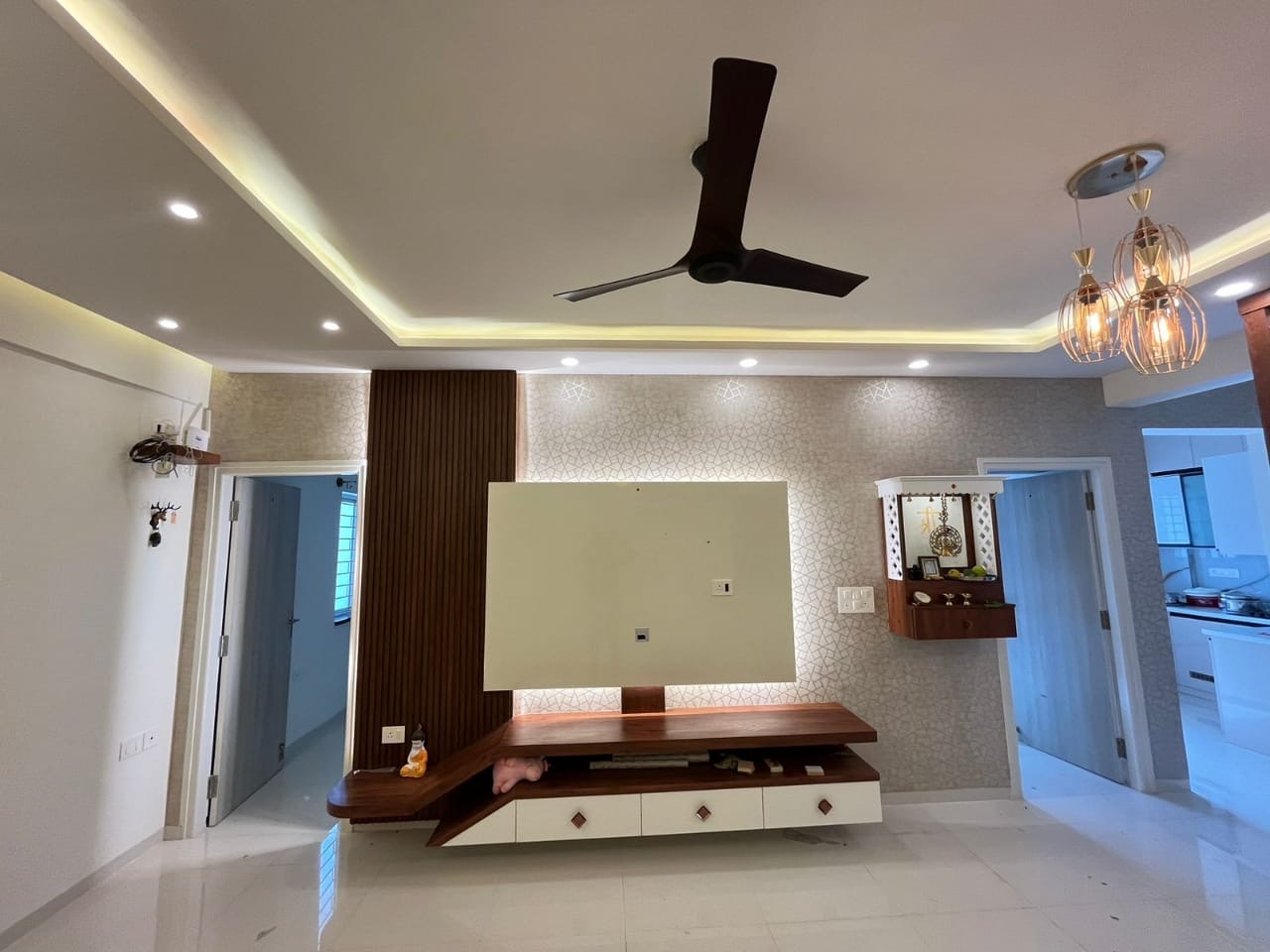 Living room TV wall with geometric wallpaper and a fluted wood accent strip, an asymmetric floating wood-and-white console
