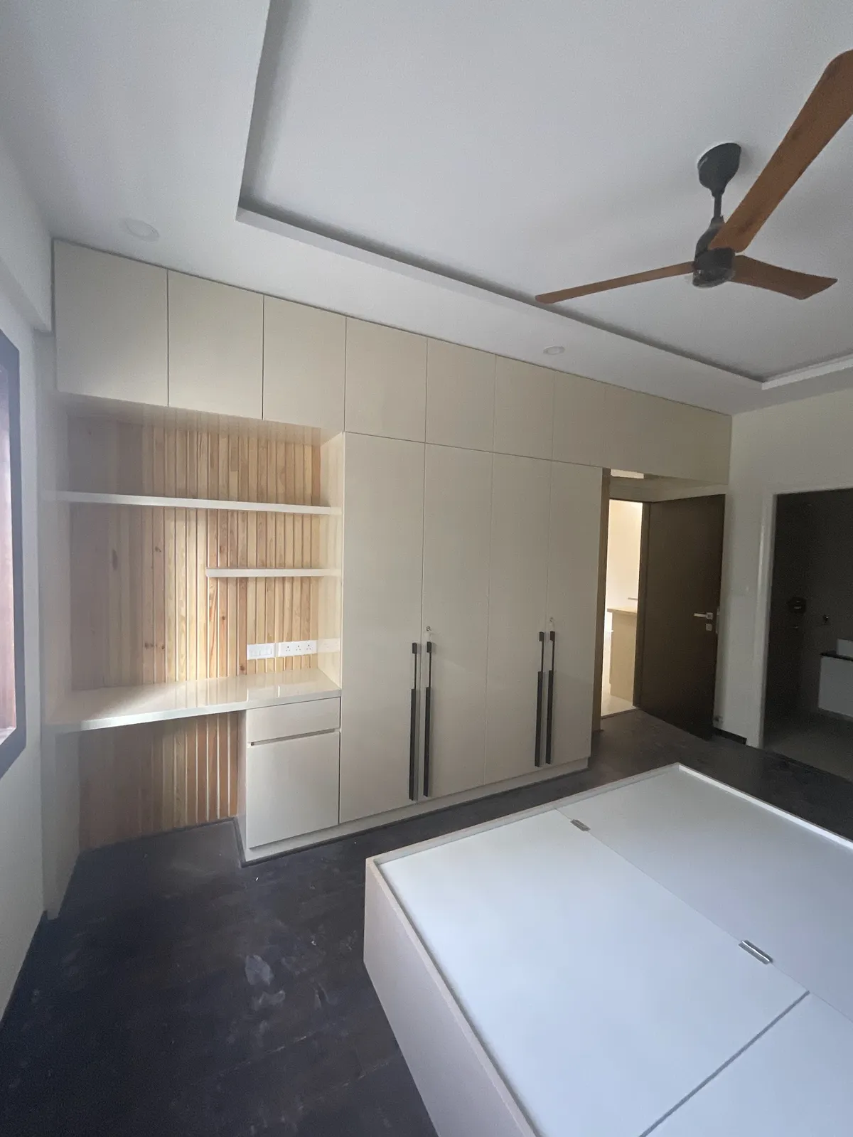 Bedroom with joinery just installed: cream matt wardrobe run with lofts and slim dark handles