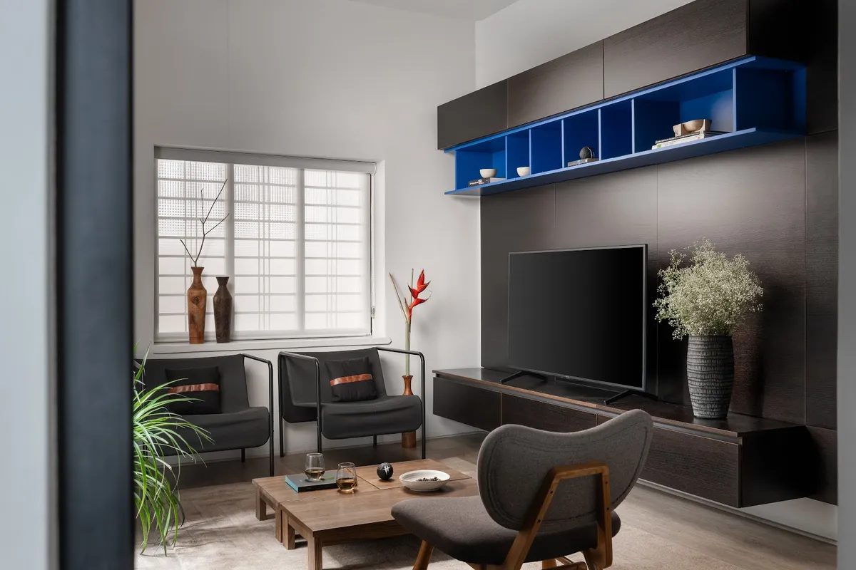 Living room where a wenge-veneer media wall carries a cobalt-blue lacquered open shelf run above the TV