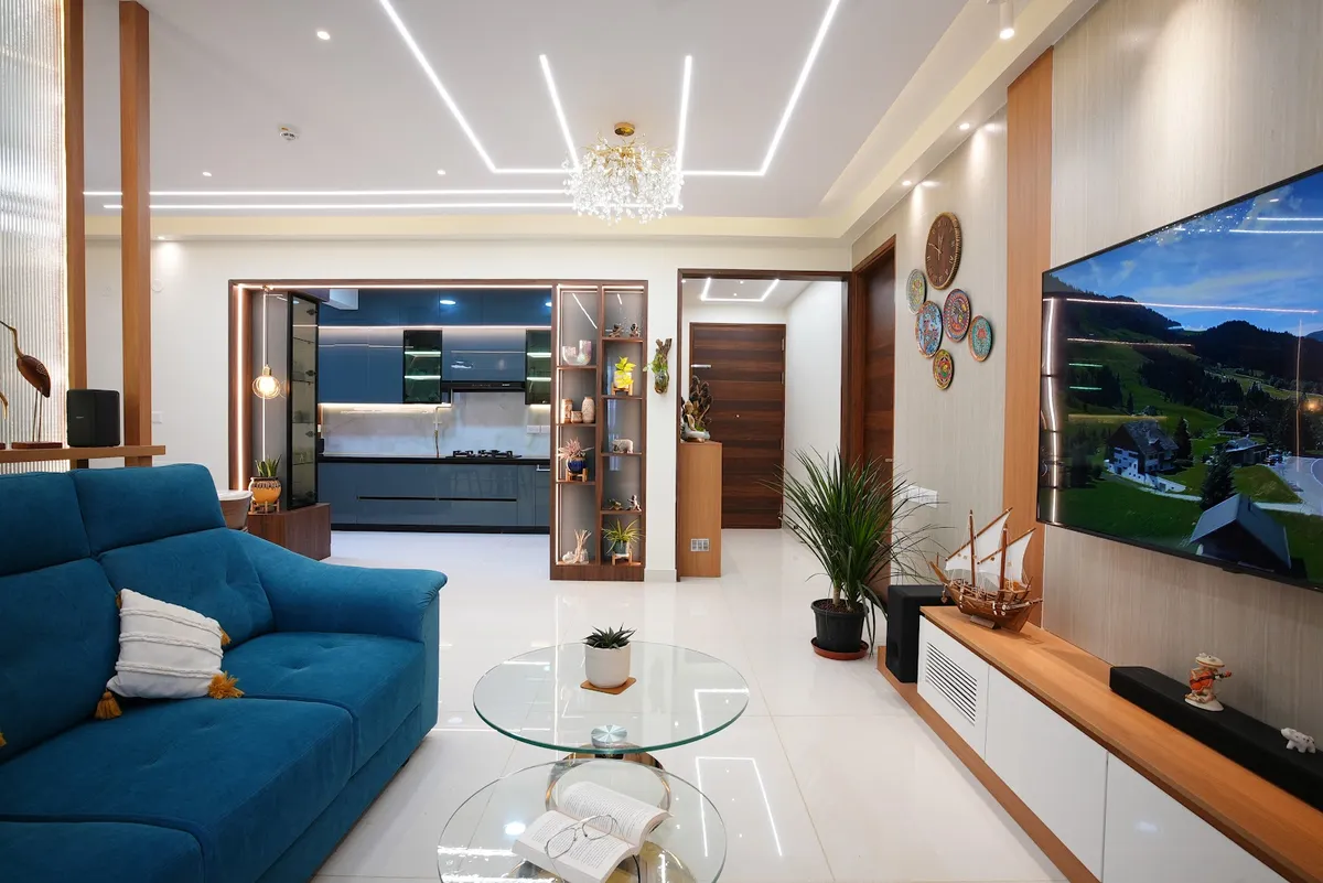 Open-plan living room with a teal sofa, a round glass coffee table, a wood-and-white TV console with decorative wall plates