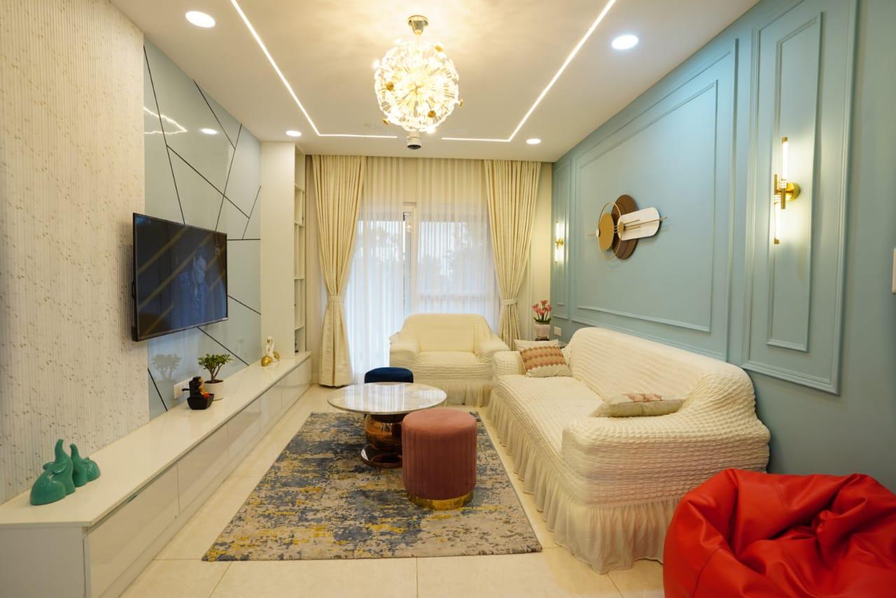 Real photo of a living room with a mint-blue moulded panel wall, brass wall sconces, a sputnik-style chandelier