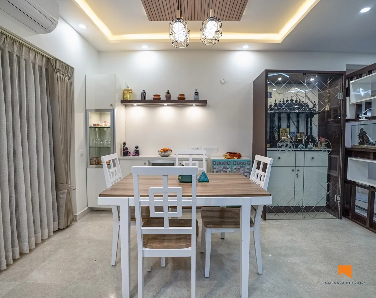 Dining room with a white-and-wood four-seater under two geometric cage pendants, a wood-slat ceiling raft with cove light