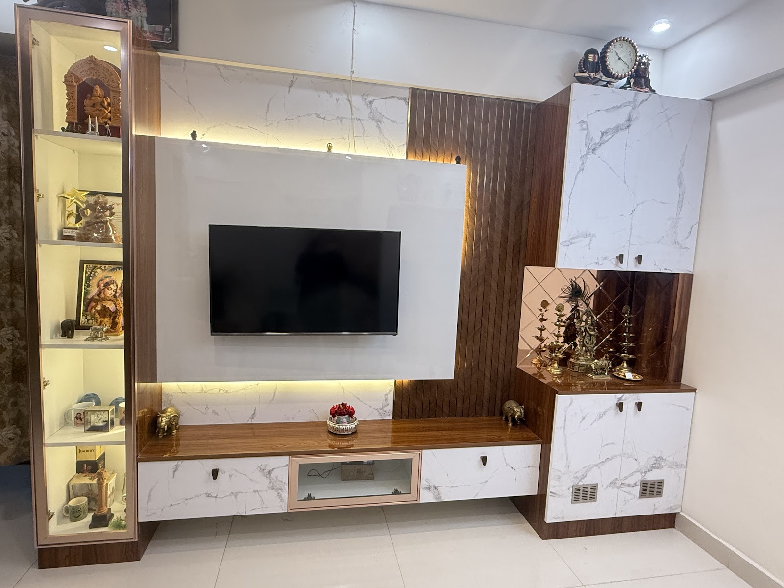 Living room TV wall unit with a marble-panel backsplash, fluted wood accent strip, LED backlighting, a glass-front trophy display cabinet