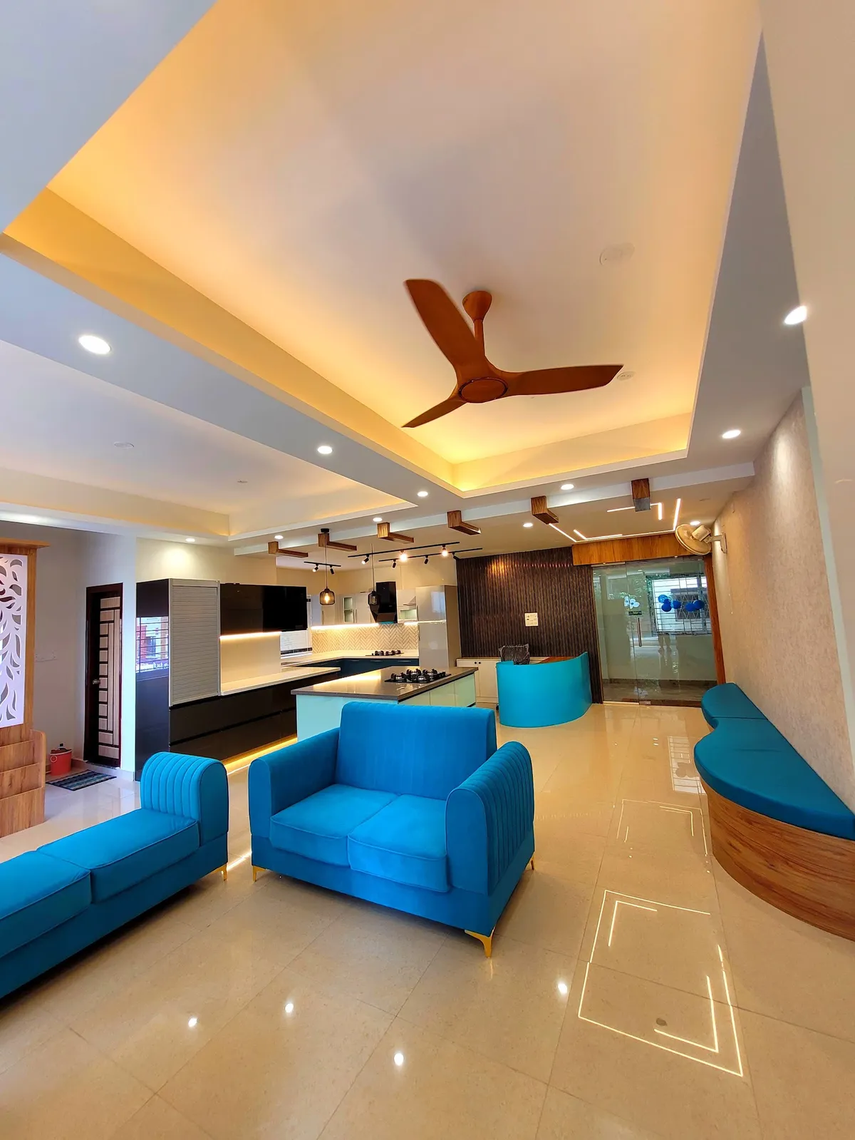 Open floor where electric-blue channel-tufted sofas sit in front of a black-and-white island kitchen