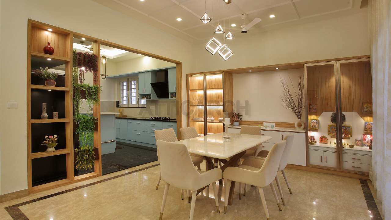 Dining room with a marble-top table for six beneath a geometric pendant chandelier, wood-framed display shelving with a lit pooja niche