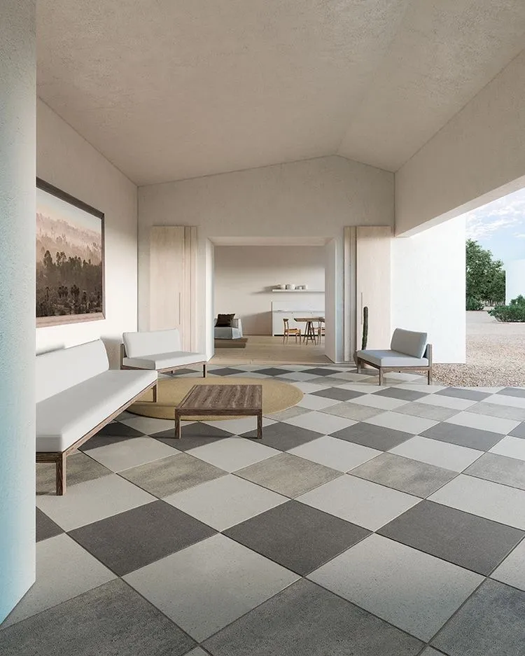 Render of a covered home veranda with a grey-and-cream checkerboard tile floor, a low wooden bench and armchairs around a round rug