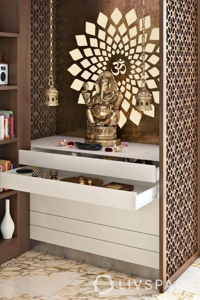 Render of a pooja unit with a gold Om sunburst backdrop, a Ganesha idol, jaali side panelling and white pull-out drawer storage below.