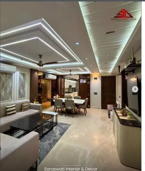 Open-plan living-dining space with a multi-tier linear-lit cove ceiling, grey L-shaped sofas around black coffee tables on a blue patterned rug