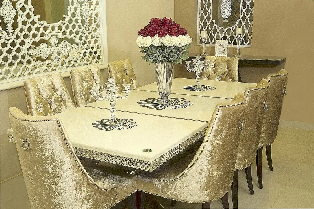 Dining corner with a cream marble-top eight-seater inlaid with dark scroll motifs on a silver-clad apron