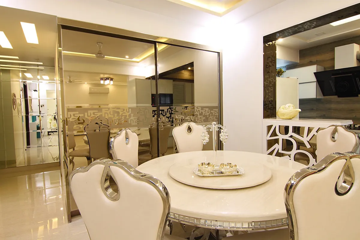 Round marble dining table with ornate cream leather and polished-chrome wingback dining chairs