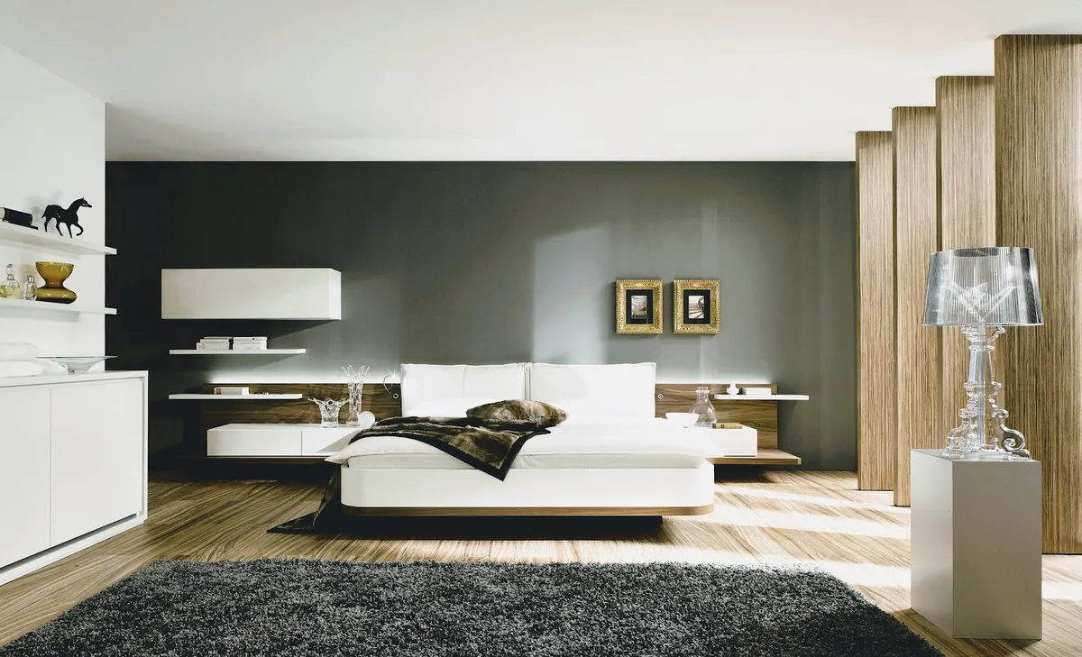 Render of a wide bedroom where a low white platform bed on a walnut plinth floats in front of a graphite feature wall