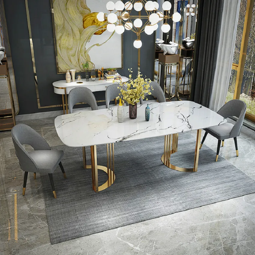 Render of a grey-and-gold dining room seen from above, a white marble-top table on twin polished brass loop bases with grey velvet chairs