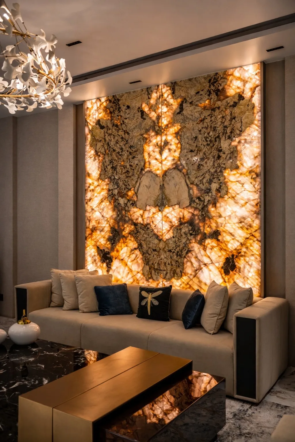 Living room with a dramatic backlit amber onyx stone feature wall, a beige sofa styled with navy and beige cushions, a brass waterfall coffee table