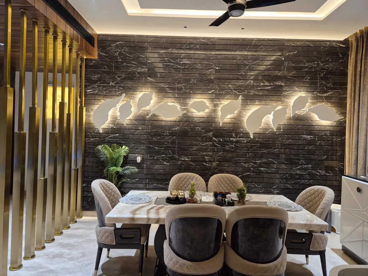 Dining room with a black marble slat feature wall backlit behind leaf-shaped decorative cutouts, a gold vertical-rod screen divider