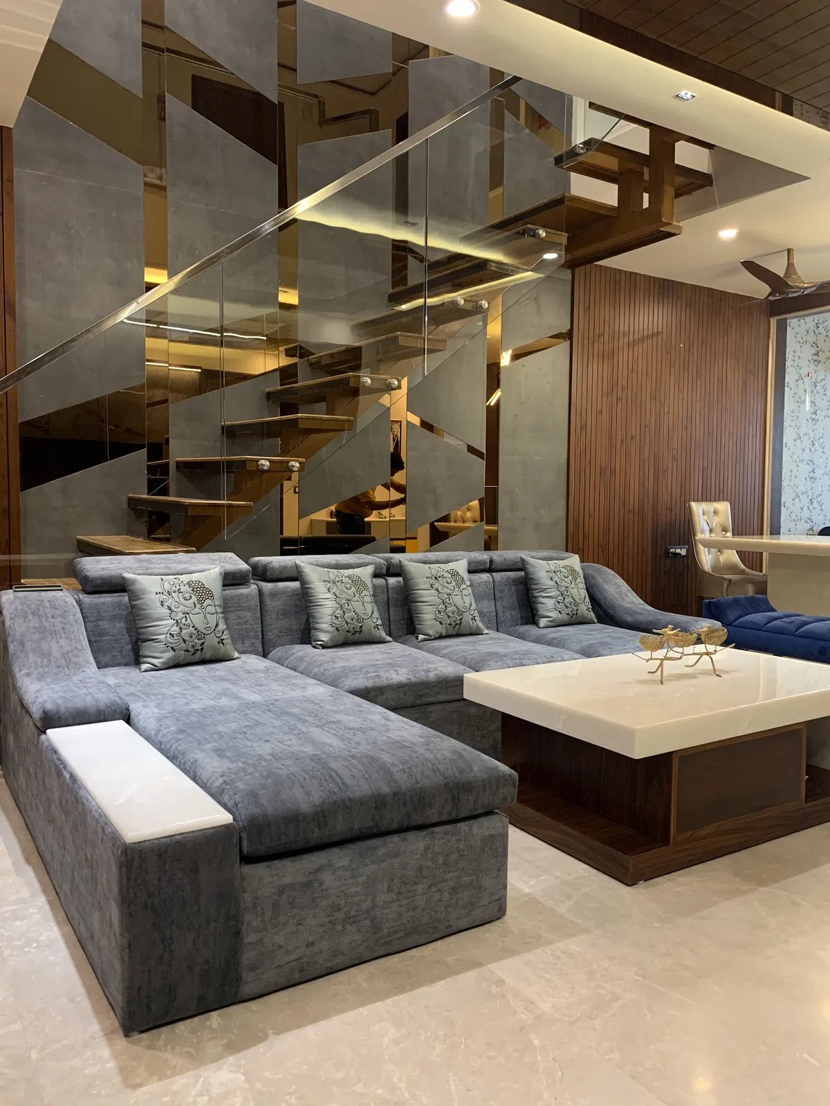 Grey chenille U-shaped sofa with printed satin cushions facing an onyx-top coffee table on a wenge base