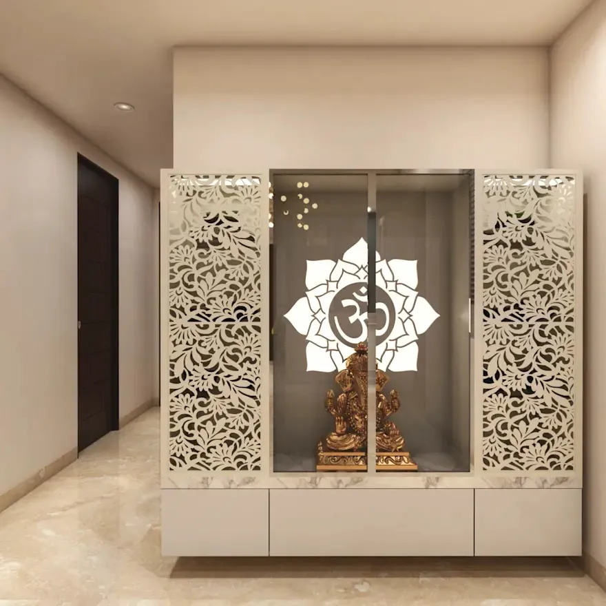 Render of a pooja unit with intricate white CNC-cut floral jaali doors, a glass panel etched with a lotus Om motif, and a brass Ganesh idol inside.