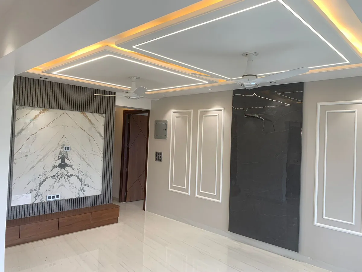Unfurnished living hall with a book-matched white marble TV backdrop set into grey fluted panelling over a floating walnut drawer console