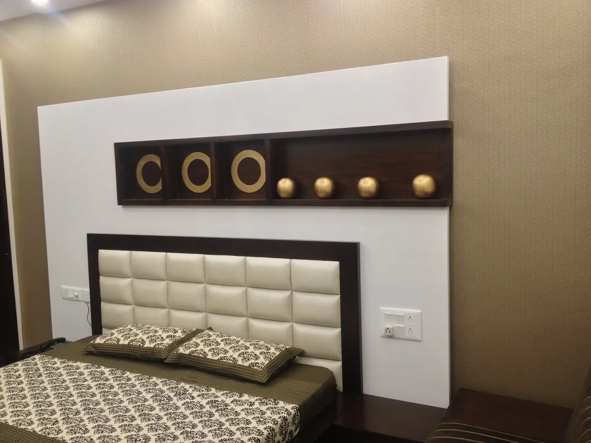 Bed with a square-tufted cream leatherette headboard in a wenge frame set against a white feature panel