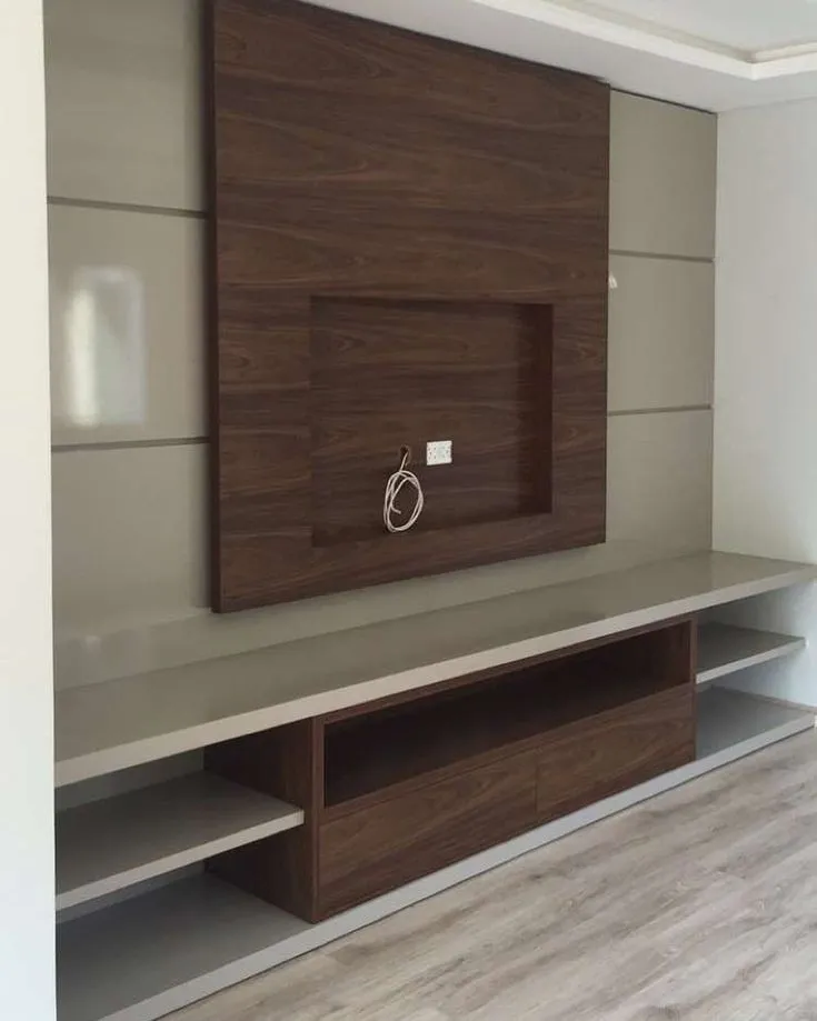 TV unit wall with a recessed wood-panel niche framed by taupe panelled walls, over a floating stone-top console with open shelving and a wood-laminate drawer