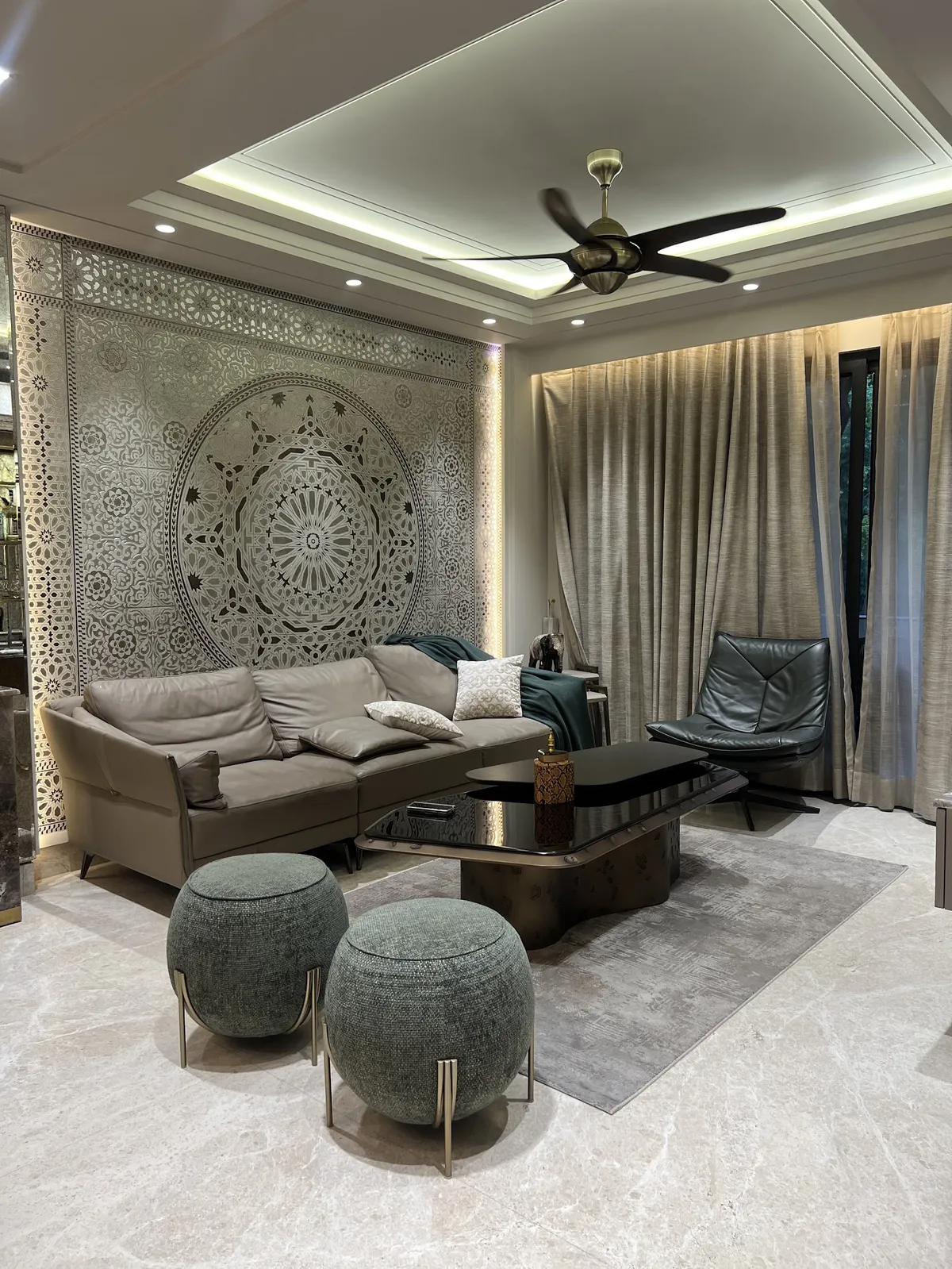 Living room with a backlit carved mandala jaali panel filling the wall behind a taupe leather sofa
