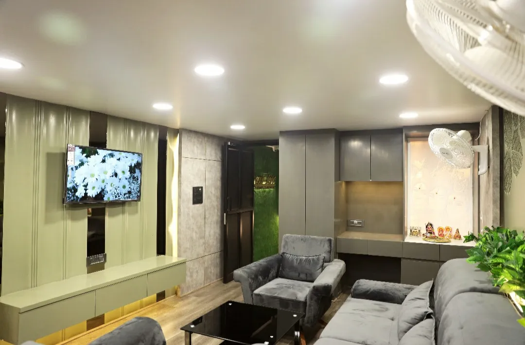 Living room with a sage-green fluted TV panel wall and matching floating console, grey velvet sofa and armchairs around a black glass table