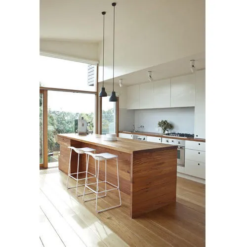 Kitchen built around a solid-timber waterfall island with two white wire bar stools, white gloss overheads and a stainless hob run along the back wall