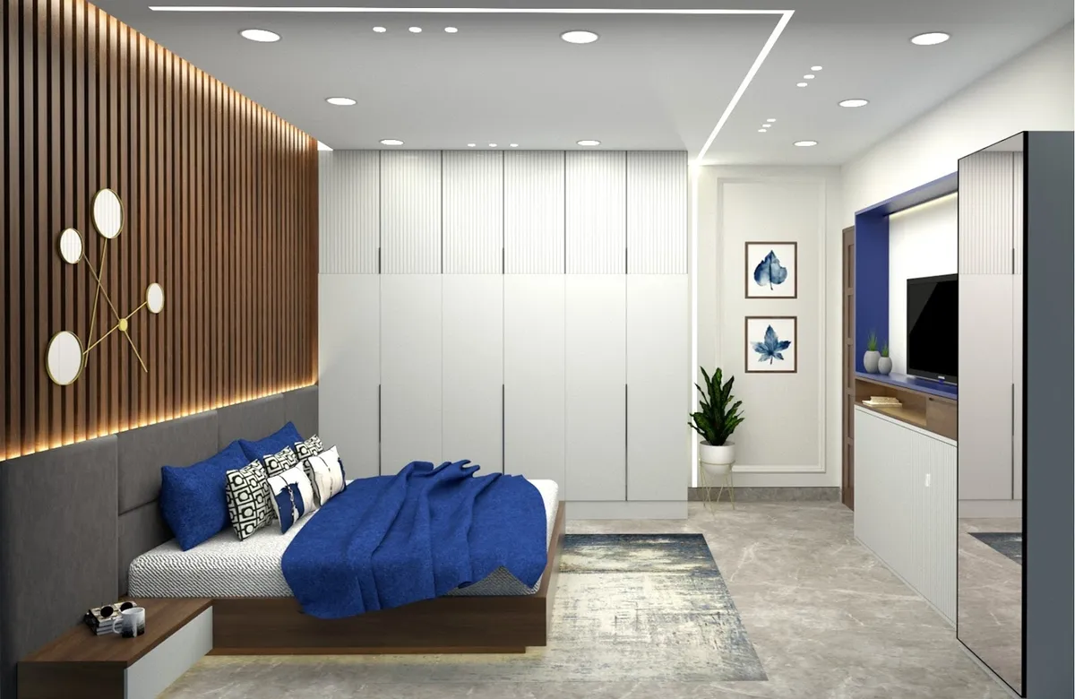 Render of a bedroom with a backlit fluted wood headboard wall and gold disc art, a white handleless wardrobe run down the long wall and a cobalt-backed TV