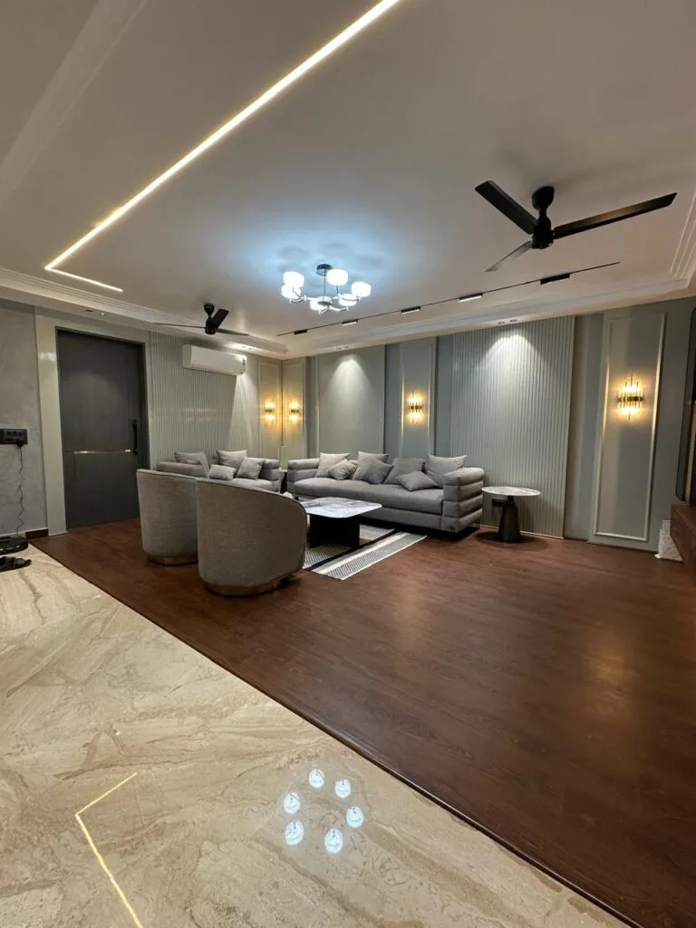 Grey sofa and two barrel swivel chairs on a raised dark-timber platform that steps down to beige marble
