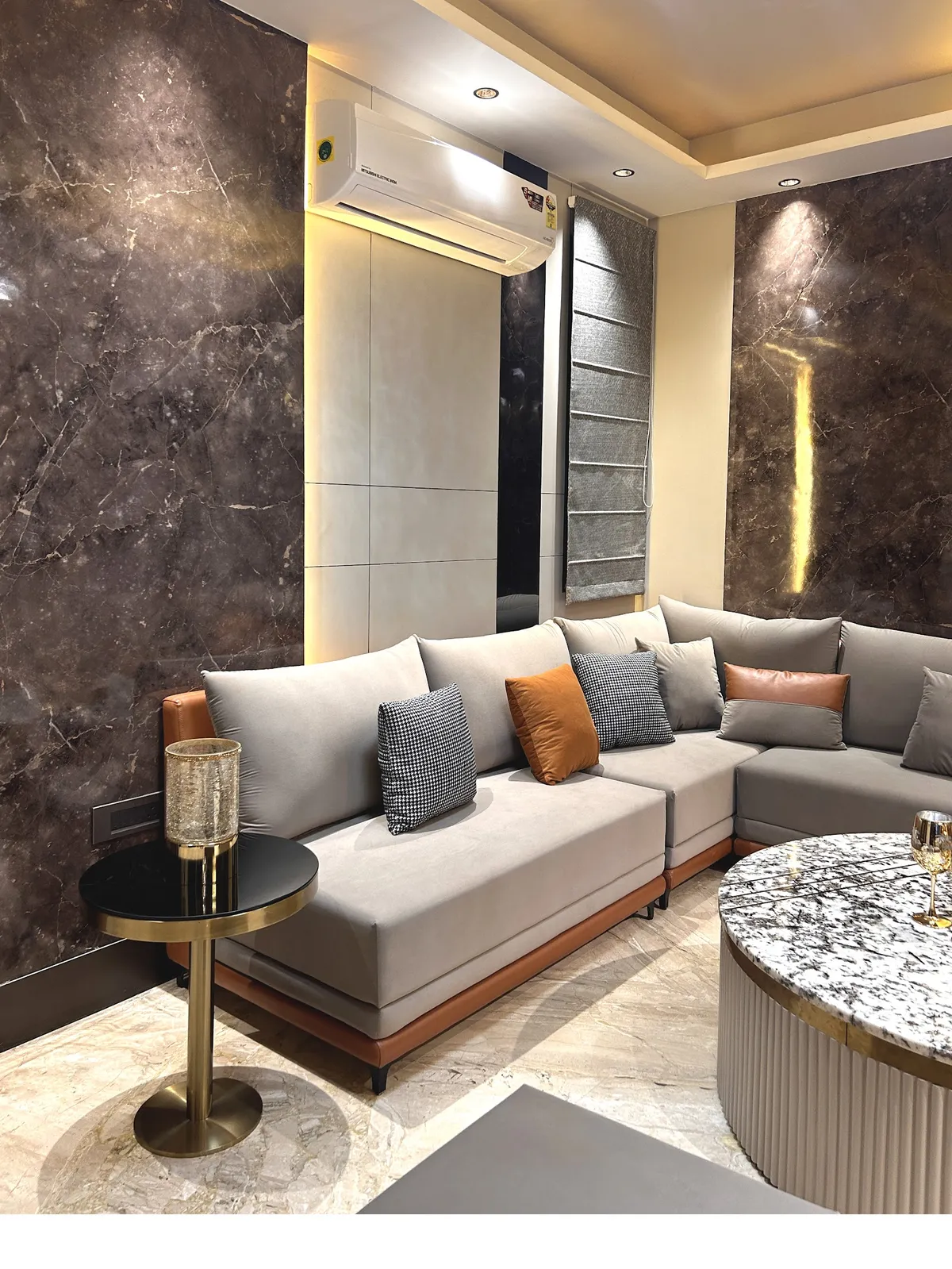 Compact living room walled in dark brown marble-effect slabs with a slim vertical gold light groove