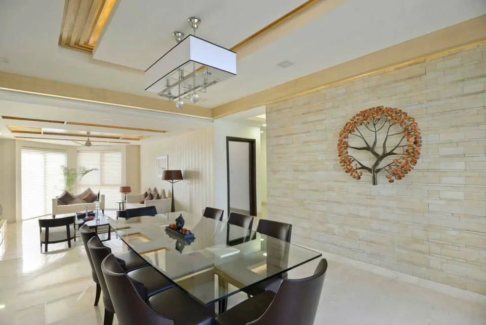 Eight-seater glass dining table with dark leather high-backs under a rectangular box pendant