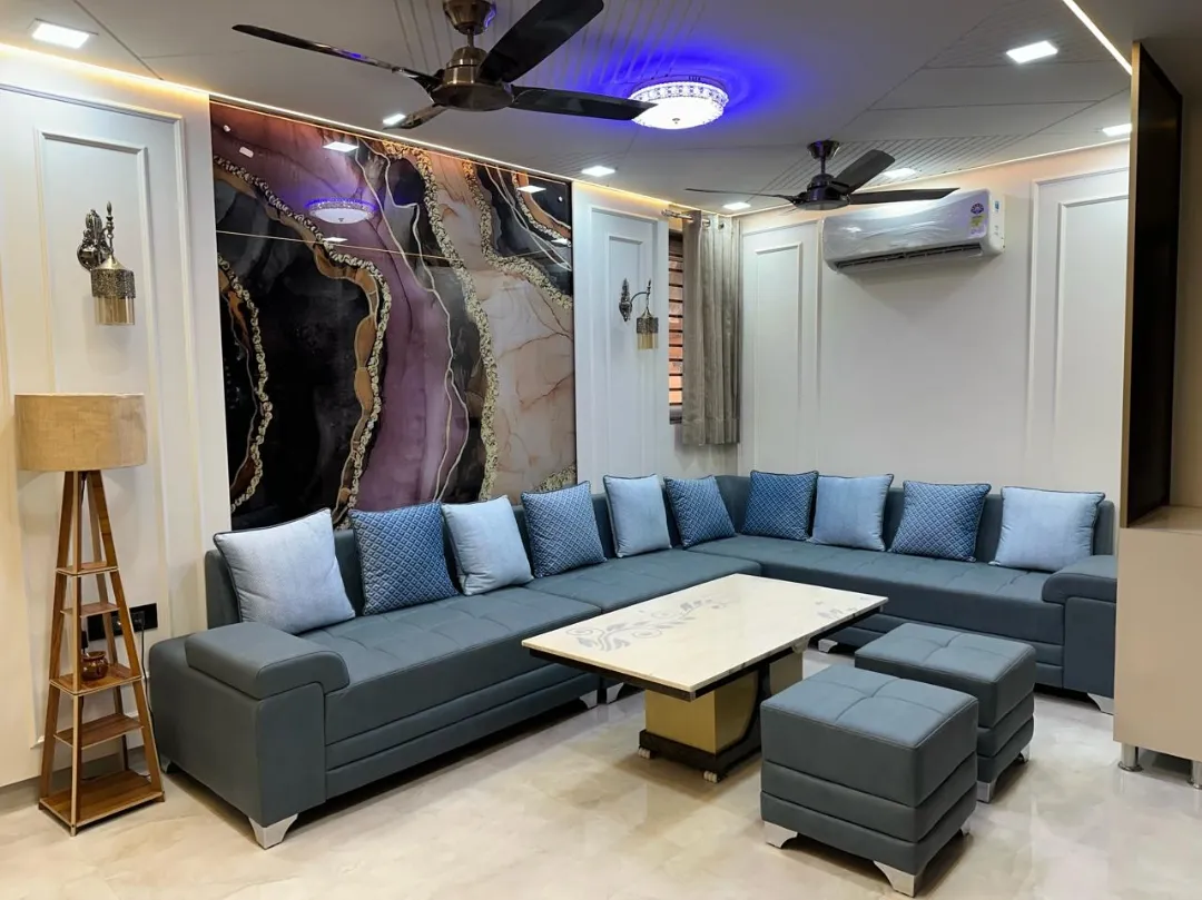 Living room with a large backlit agate-pattern resin wall art panel, panel-moulded walls, a blue-grey tufted L-sofa
