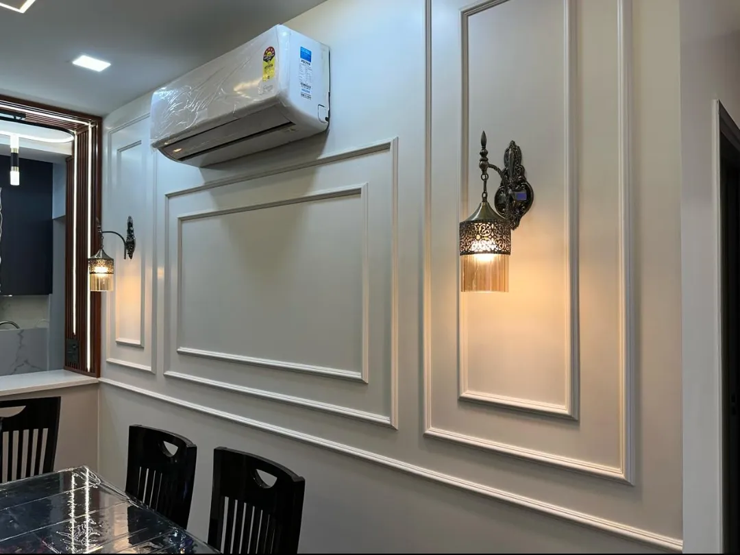 Dining wall in cream with applied rectangular mouldings and two antique-brass sconces with fluted glass shades