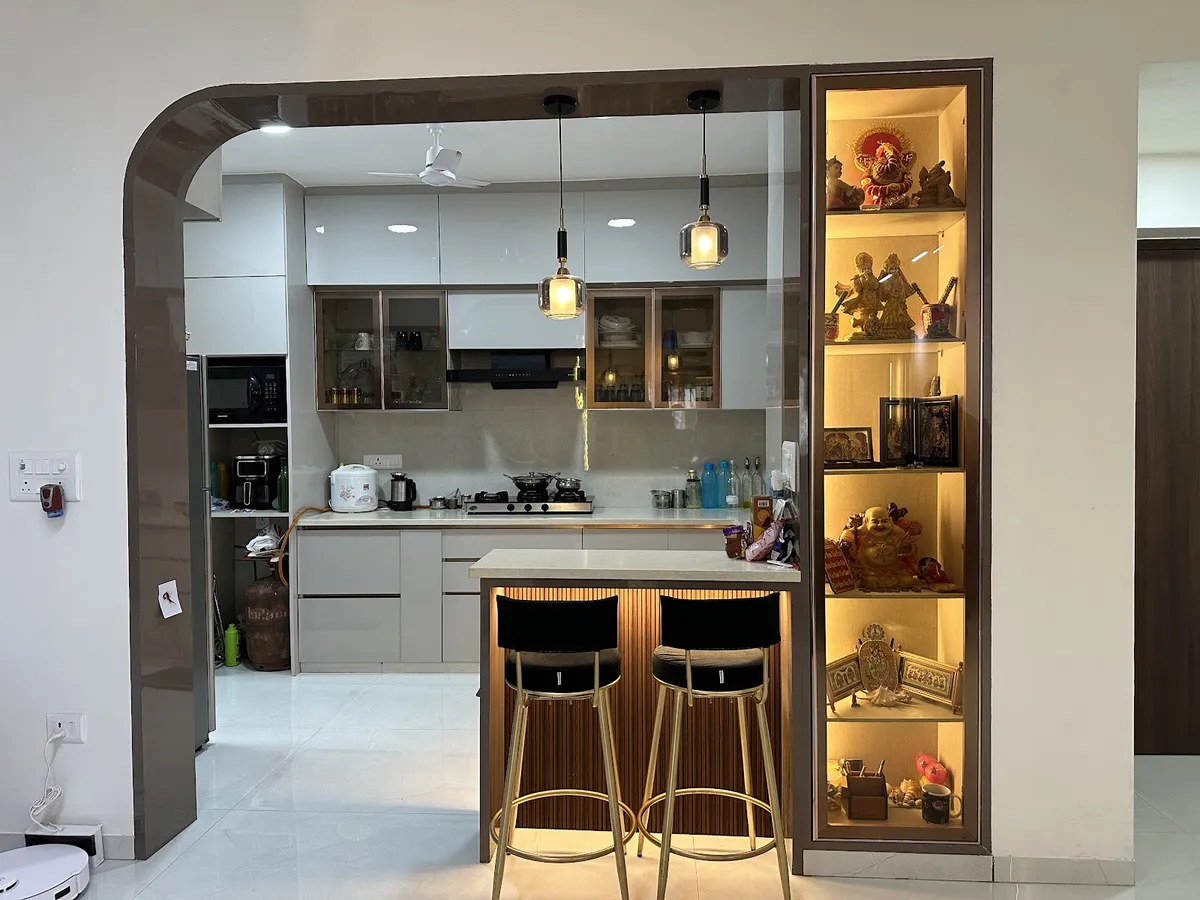 Lived-in open kitchen framed by a curved dark high-gloss arch, with a fluted-wood breakfast counter and two black bar stools in front