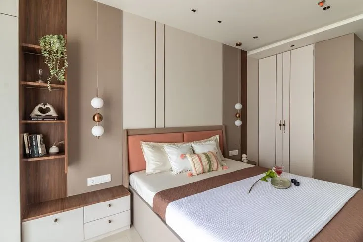 A bedroom with a terracotta upholstered headboard against taupe wall panelling, globe pendant lights