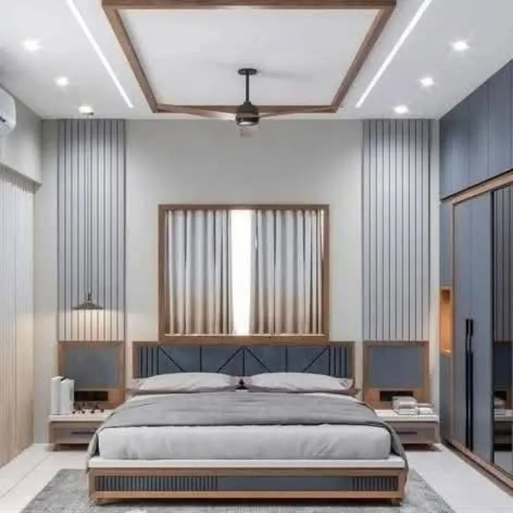 A bedroom with a navy upholstered headboard set between fluted wood-panelled walls, a mirrored sliding wardrobe