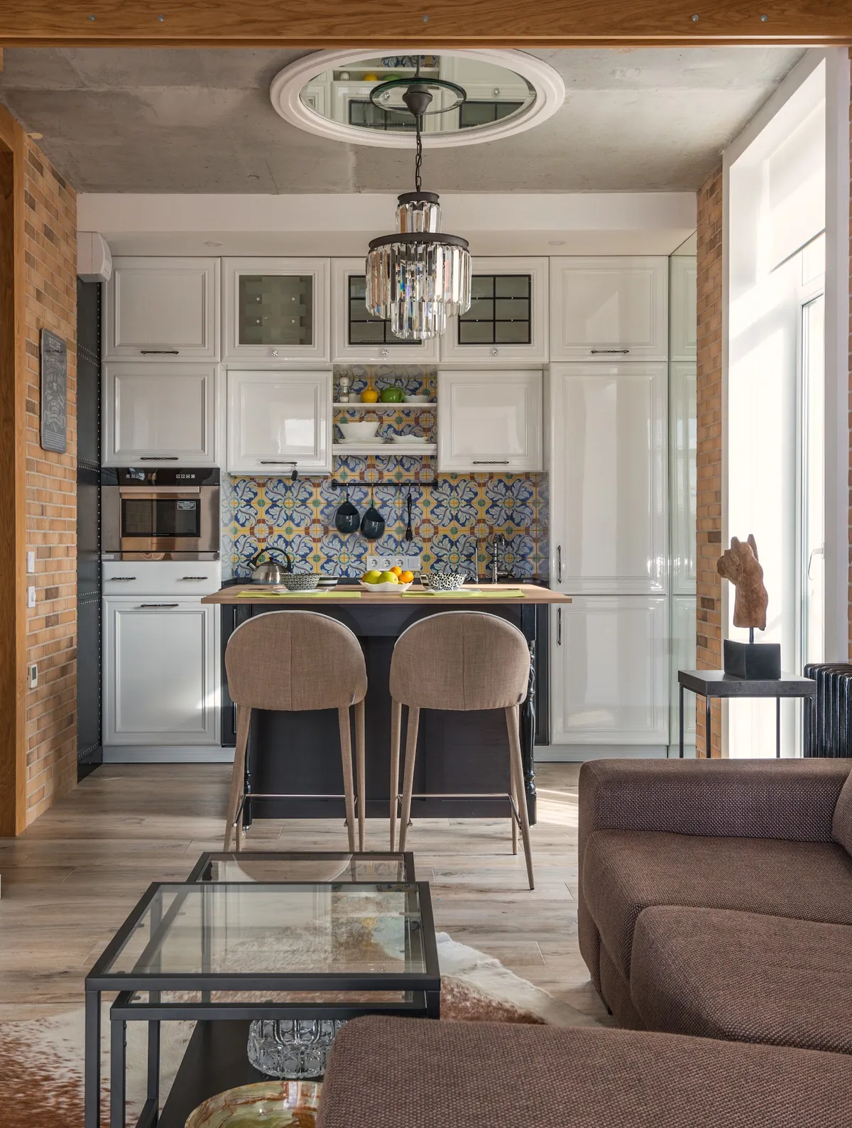 Open-plan loft flat where a white raised-panel kitchen with a blue-and-yellow azulejo backsplash sits under a raw concrete slab