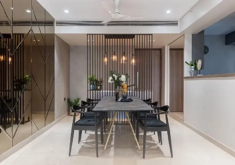 Grey marble-top dining table on a brass X-frame with black metal-and-cane armchairs