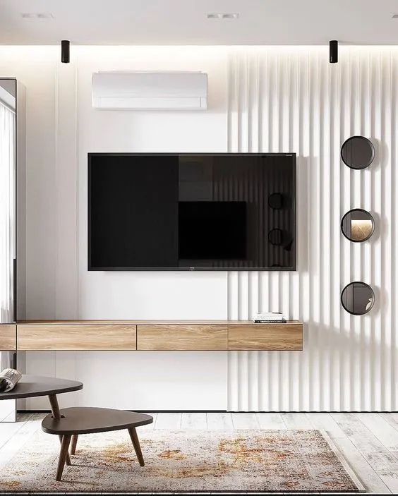 Render of a living room TV wall with white fluted panelling, a floating wood console, and three round mirror discs beside the screen.