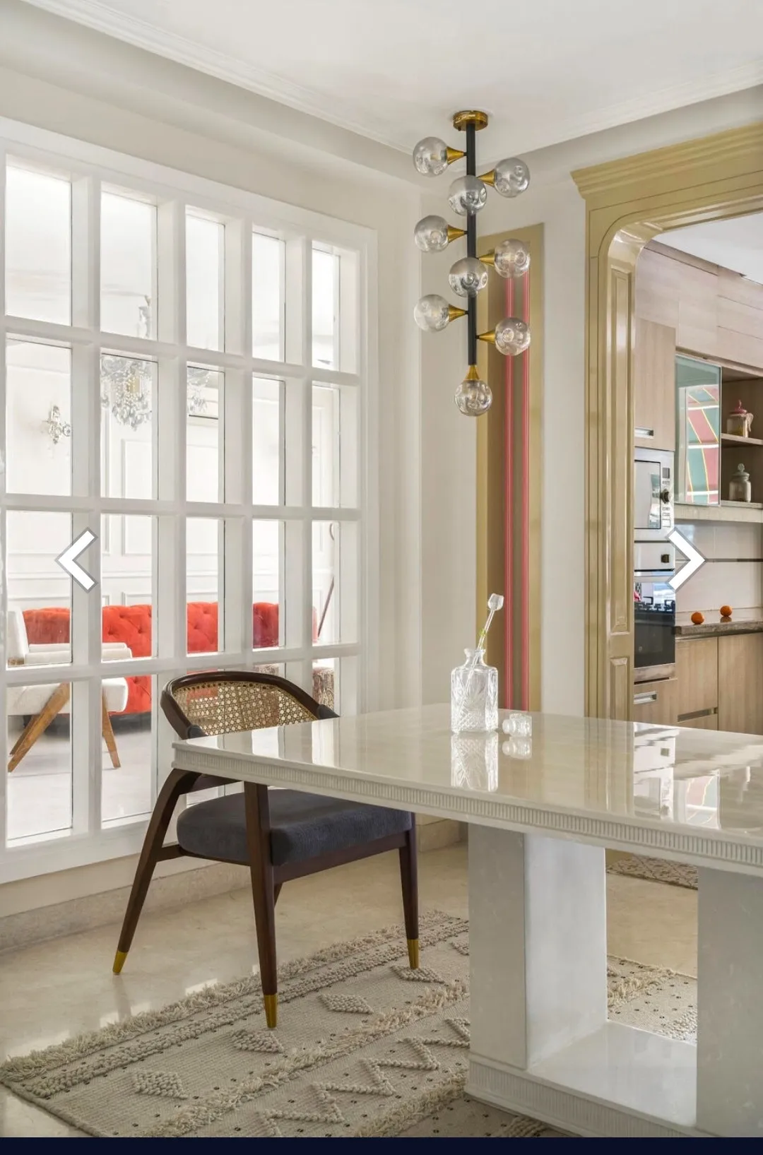 Render of a dining nook with a cane-back chair and marble-top table under a brass multi-globe pendant light