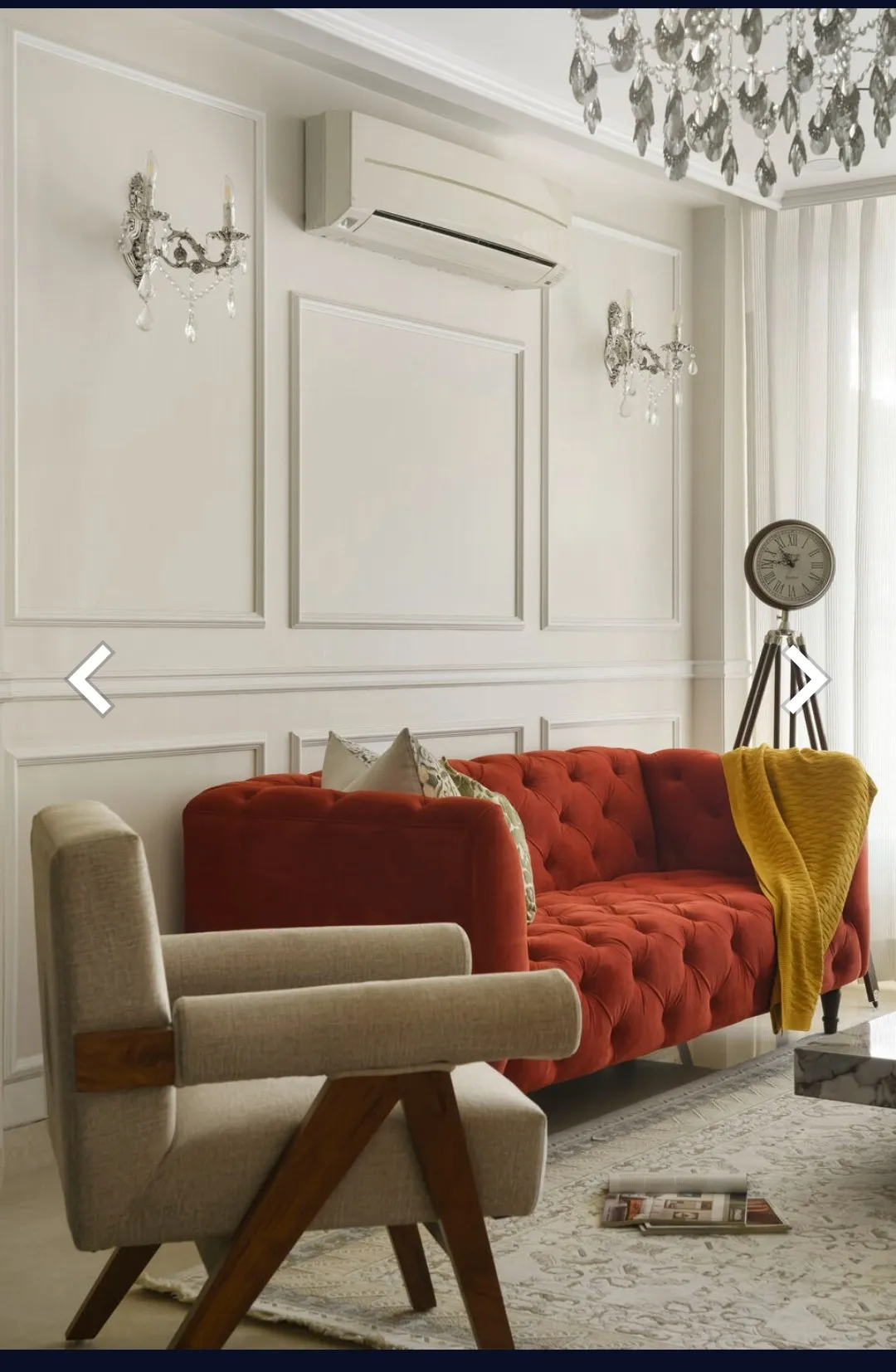 Ivory moulding-panelled living room with a rust-red button-tufted chesterfield, a mustard throw over one arm