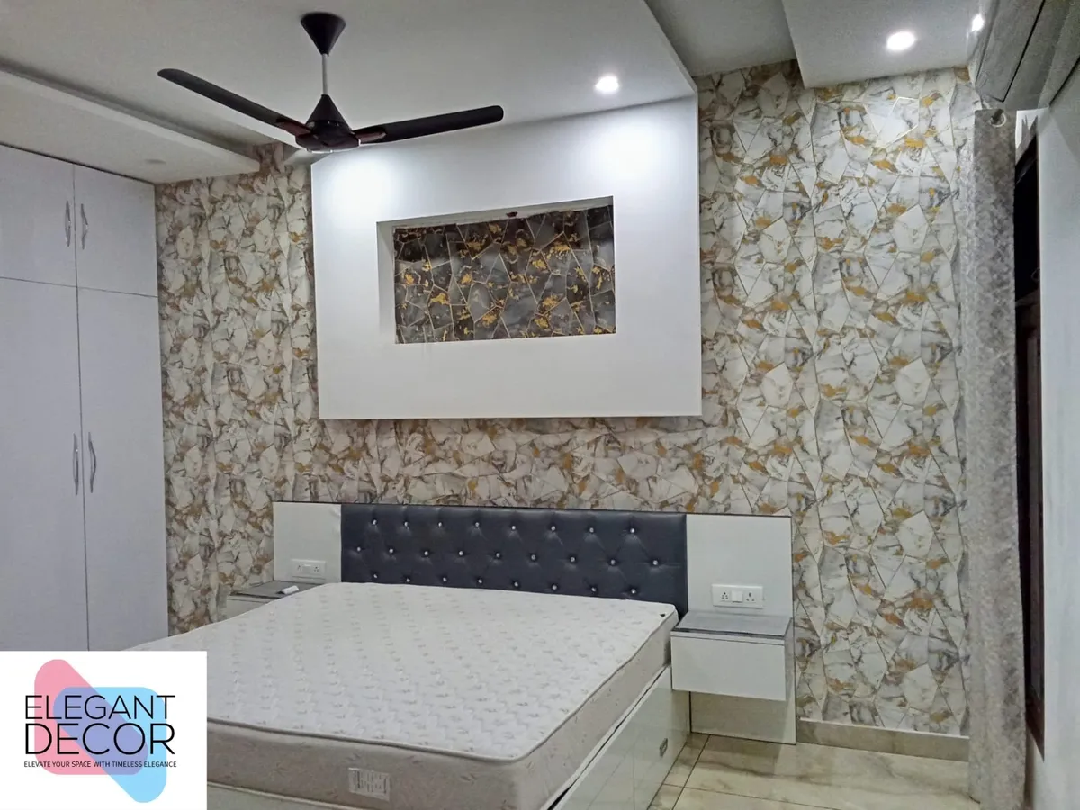 Bedroom with gold-veined marble-pattern wallpaper covering the full wall, a recessed art niche above a black tufted-leather headboard