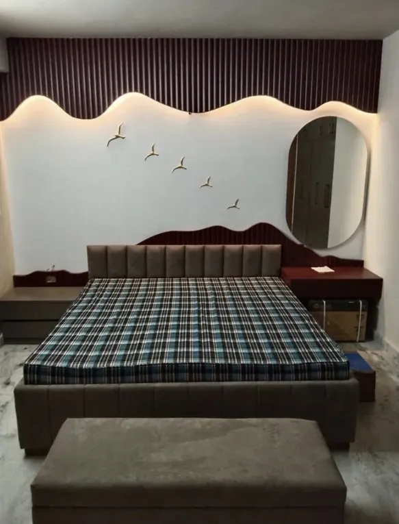 Bedroom with a wave-shaped fluted wood panelled headboard wall, cove lighting, a flock of bird wall art, and a round mirror beside the bed.