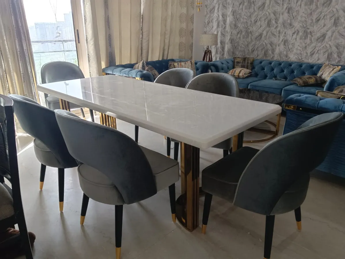 Six-seater white marble dining table on a mirror-gold pedestal base with grey velvet chairs