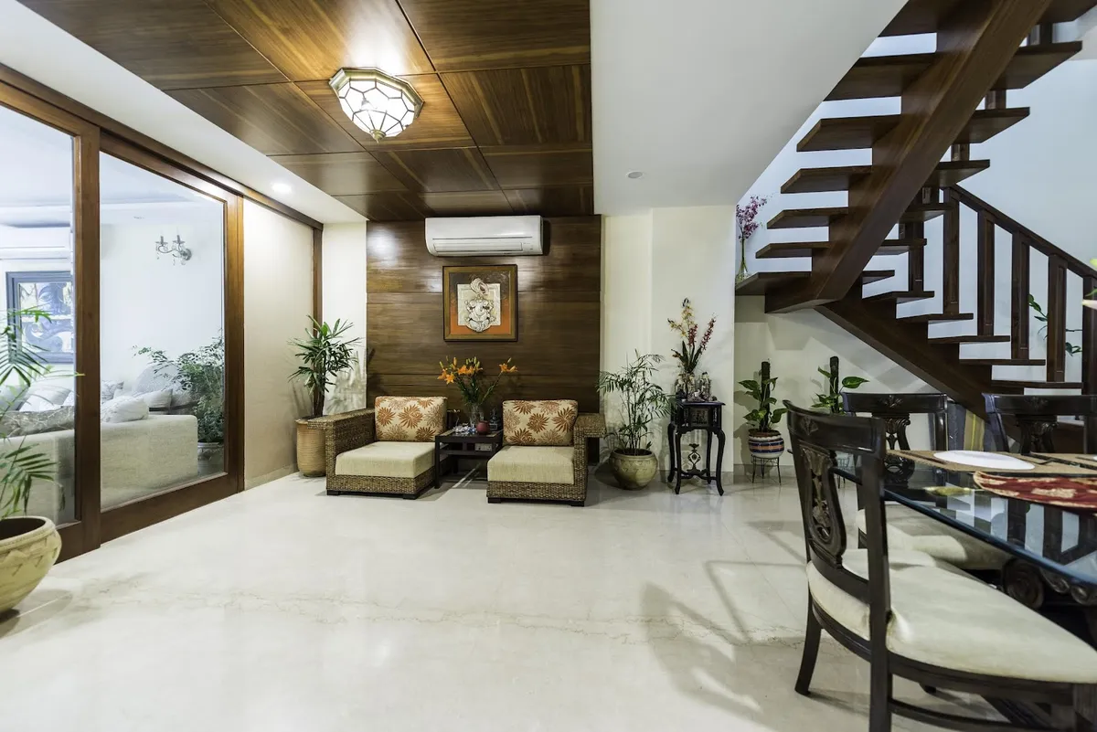 Teak-clad lounge corner with two cane-and-teak armchairs in printed upholstery under a wood-planked ceiling, a framed Ganesha relief between them