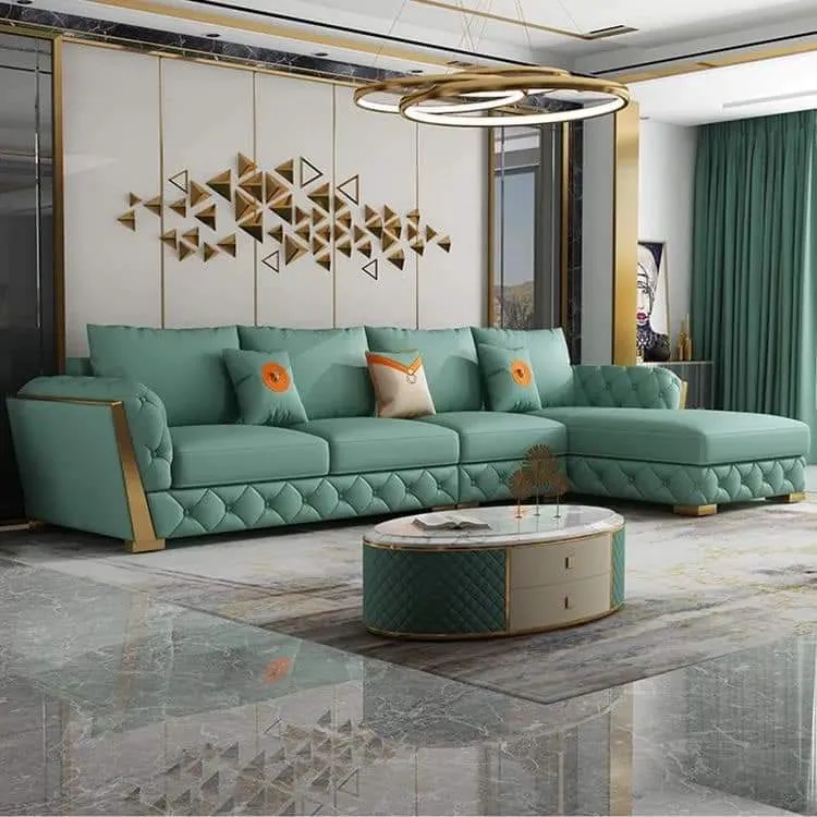 Render of a living room with a teal tufted sectional sofa on gold legs, a geometric gold triangle wall-art installation, and a marble-effect floor.
